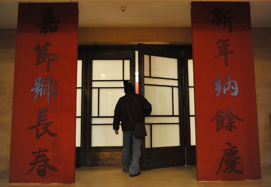 A citizen enters the exhibiton hall of the "Calligraphy Inheriting--New Year Couplet Calligraphy Exhibition" at the National Art Museum of China in Beijing, capital of China, Jan. 18, 2013. The exhibition kicked off on Friday, displaying over a hundred couplet works.(Xinhua/Lu Peng) 