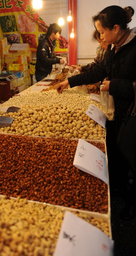 People buy nuts during the second Guiyang spring festival shopping fair in Guiyang, capital of southwest China's Guizhou Province, Jan. 19, 2013. The fair which would last from Jan. 19 to Feb. 6 attracts the participation of more than 400 enterprises, providing special goods for the Spring Festival use. (Xinhua/Tao Liang)  