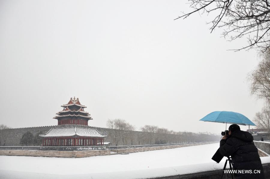 A photographer takes photos of a snow-covered watchtower of the Palace Museum, also known as the Forbidden City, in Beijing, capital of China, Jan. 20, 2013. A snow hit the capital city on Sunday. (Xinhua/Wang Junfeng) 