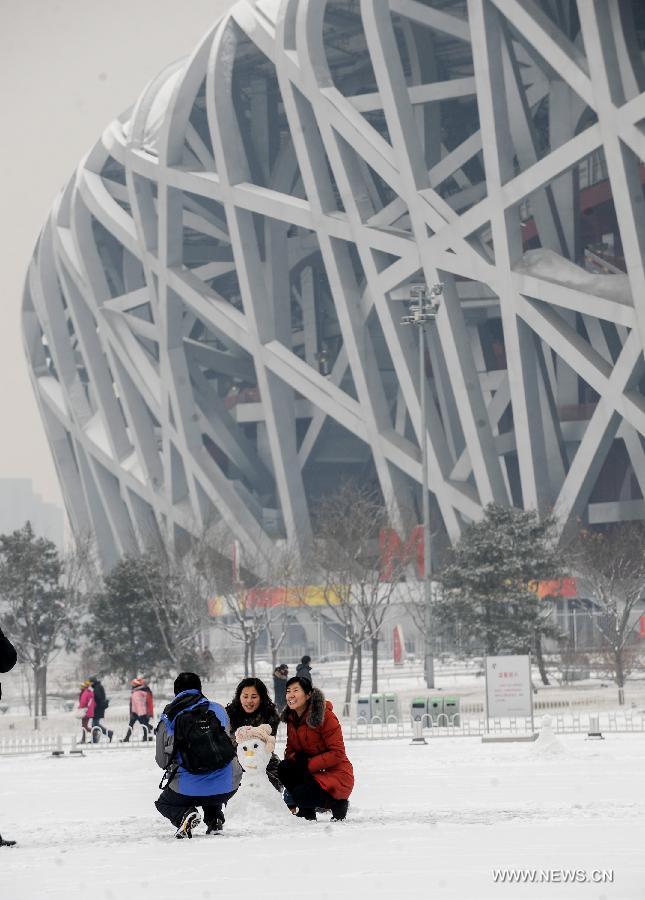 Visitors pose for photos with a snowman at the Beijing Olympic Park in Beijing, capital of China, Jan. 20, 2013. A snow hit the capital city on Sunday. (Xinhua/Zhang Yu)