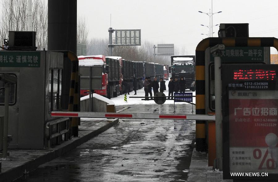 Drivers stand outside the entrance of the Beijing-Kunming Expressway to wait for traffic reopening in Tangxian County, north China's Hebei Province, Jan. 20, 2013. Snow fell in most parts of Hebei Province on Jan. 19 evening and 19 expressways in the province have been closed. (Xinhua/Zhu Xudong)