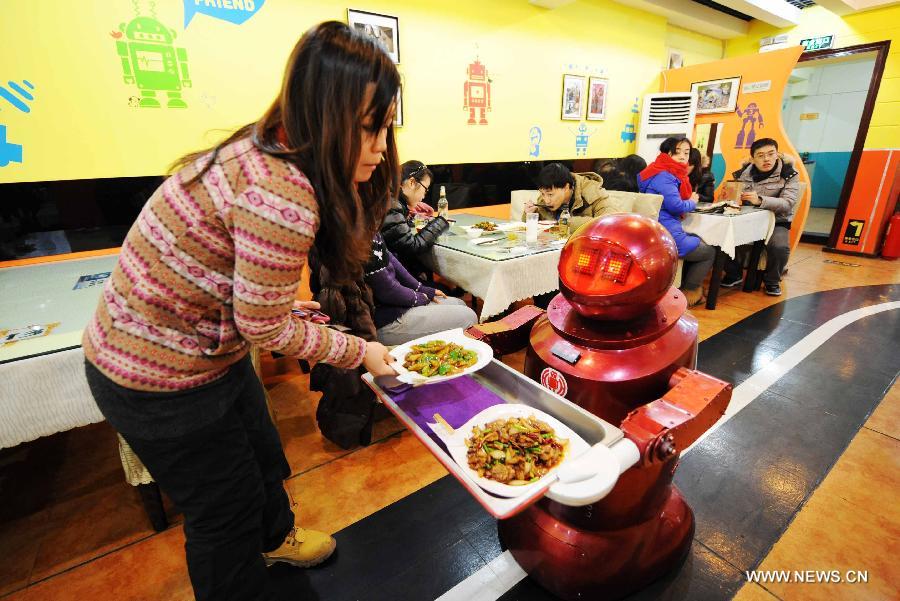 A robot serves dishes to a customer in a robot themed restaurant in Harbin, capital of northeast China's Heilongjiang Province, Jan. 18, 2013. Opened in June of 2012, the restaurant has gained fame by using a total of 20 robots to cook meals, deliver dishes and greet customers. (Xinhua/Wang Jianwei) 