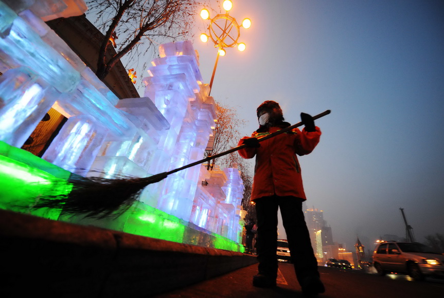 Yanng Weixia, sweeps the street beside an ice lantern on Jan. 16, 2013. (Xinhua/Wang Jianwei) 