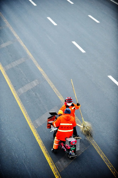 Yanng Weixia, a sanitation worker, puts garbage into the rubbish bin on Jan. 16, 2013. (Xinhua/Wang Jianwei)