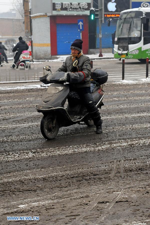 A man rides on a snow-covered road in Taiyuan City, capital of north China's Shanxi Province, Jan. 21, 2013. Snowfall hit Taiyuan at the weekend. (Xinhua/Fan Minda)