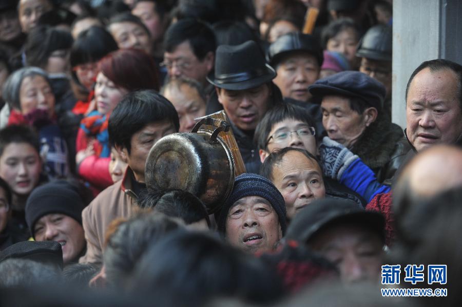 Free Laba porridge is given out in the Lingyin Temple in Hangzhou on Jan. 19, 2013. Numerous people, however, failed to queue up and made the scene a mess. Thanks to the emergent measures taken by the guards, no people were injured.(Photo/Xinhua)