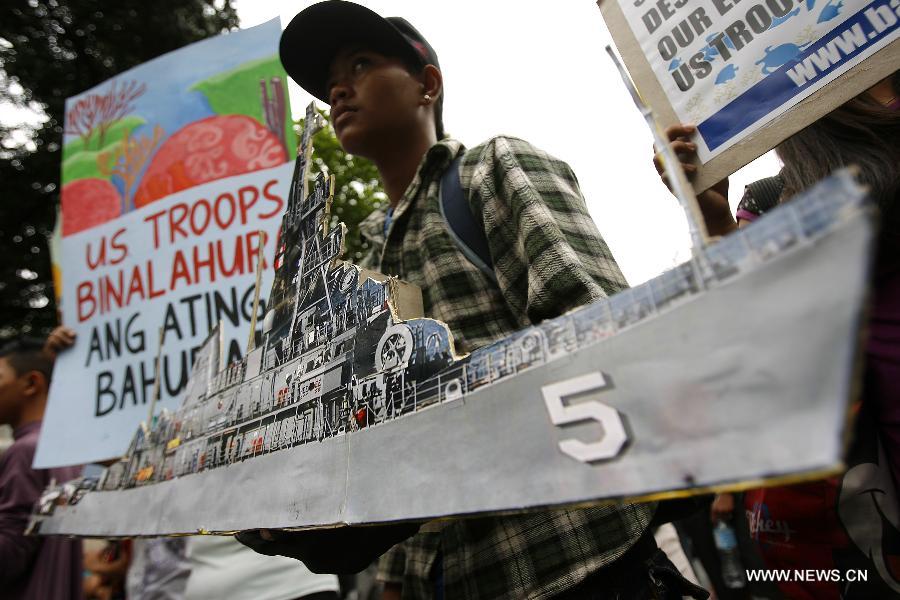 An activist holds a picture of the USS Guardian during a rally near the U.S. Embassy in Manila, the Philippines, Jan. 21, 2013. The protesters called for the pullout of U.S. troops in the Philippines after the U.S. Navy minesweeper USS Guardian (MCM 5) ran aground on Tubbataha Reef. (Xinhua/Rouelle Umali) 