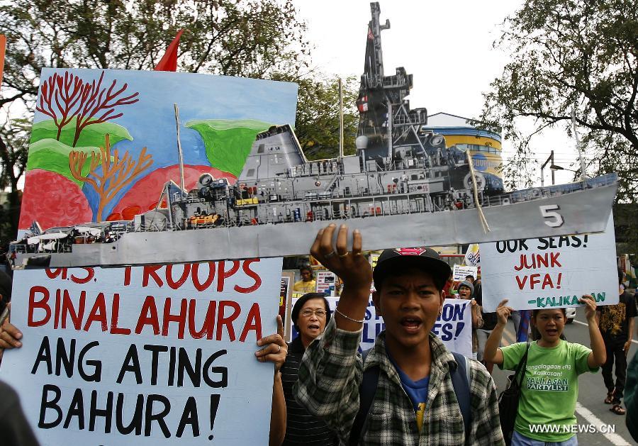 Activists shout slogans as one of them holds a picture of the USS Guardian during a rally near the U.S. Embassy in Manila, the Philippines, Jan. 21, 2013. The protesters called for the pullout of U.S. troops in the Philippines after the U.S. Navy minesweeper USS Guardian (MCM 5) ran aground on Tubbataha Reef. (Xinhua/Rouelle Umali)  