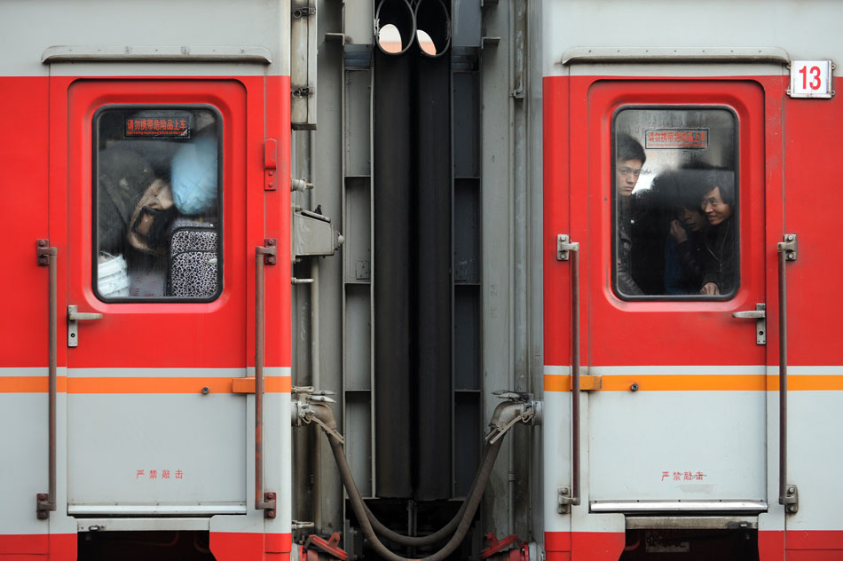 Several passengers look through the window of a train departing from Ningbo for Chongqing, Jan. 17. Some migrant workers have started to return home in order to avoid the Spring Festival travel peak that begins on Jan. 26 and will last for about 40 days. (Xinhua/Ju Huanzong)