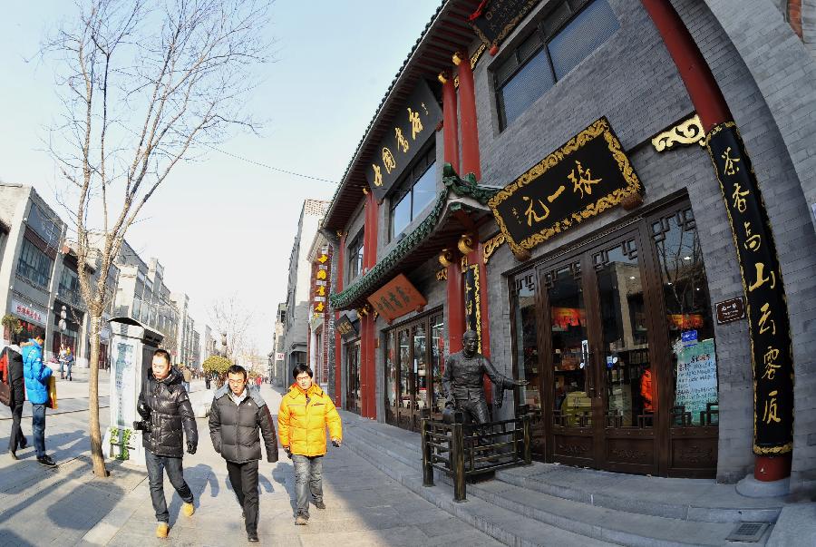 People walk past stores of famous traditional brands in the Qianmen Street in Beijing, capital of China, Jan. 21, 2013. (Xinhua/Li Xin) 