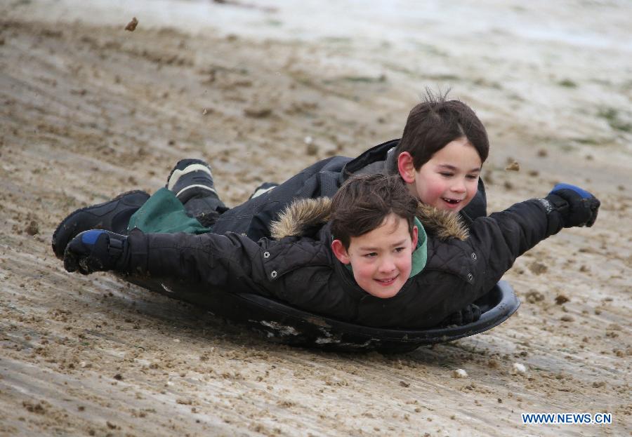 Two children sledge in the snow in Primrose Hill Park in London, Britain, Jan. 21, 2013. (Xinhua/Yin Gang)