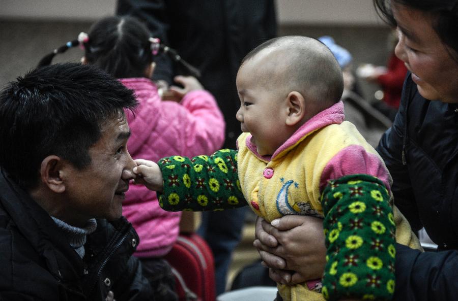 Tian Xingfu (C), an 11-month-old boy from Huaihua in central China's Hunan Province, waits for the train home with his parents at Hangzhou train station in Hangzhou, capital of east China's Zhejiang Province, Jan. 22, 2013. Many migrant workers and their children have started to return home in order to avoid the Spring Festival travel peak that begins on Jan. 26 and will last for about 40 days. The Spring Festival, the most important occasion for a family reunion for the Chinese people, falls on the first day of the first month of the traditional Chinese lunar calendar, or Feb. 10 this year. (Xinhua/Han Chuanhao)
