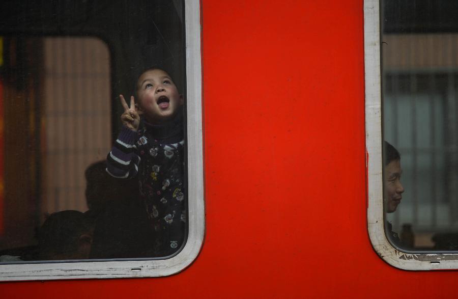 A child plays by the side of a window on a train from Ningbo of Zhejiang to Bengbu of east China's Anhui Province in Hangzhou, capital of east China's Zhejiang Province, Jan. 22, 2013. Many migrant workers and their children have started to return home in order to avoid the Spring Festival travel peak that begins on Jan. 26 and will last for about 40 days. The Spring Festival, the most important occasion for a family reunion for the Chinese people, falls on the first day of the first month of the traditional Chinese lunar calendar, or Feb. 10 this year. (Xinhua/Han Chuanhao)