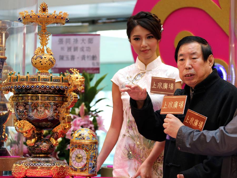 Artist Zhang Tonglu (R), introduces a cloisonne work he made during an exhibition in south China's Hong Kong, Jan. 22, 2013. An exhibition of Zhang Tonglu's cloisonne art works was held here on Tuesday, showing 22 pieces of cloisonne works. (Xinhua/Li Peng) 