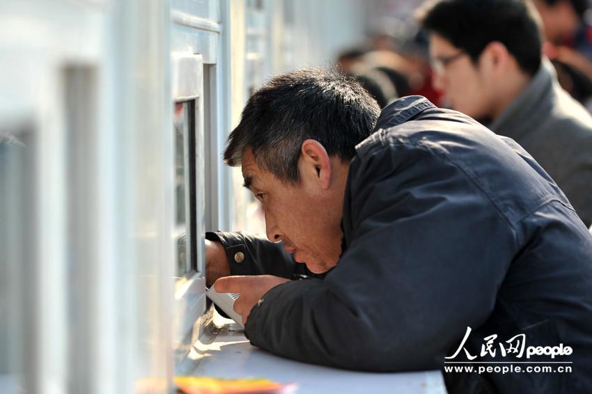 Homecoming people buy train ticket with anxiety outside a temporary ticket booth set at Beijing Railway Station, Jan. 22. The Spring Festival travel peak is going to begin on Jan. 26 and will last about 40 days. Railway passenger trips are expected to hit 225 million during the upcoming travel peak. (People’s Daily Online/Weng Qiyu)