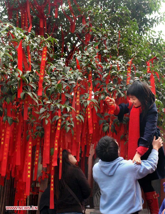 File photo taken on Feb. 12, 2006 shows people tie blessing red ribbons onto a "blessing tree" at a temple fair in Zhengzhou, capital of central China's Henan Province. Temple fair in central China area is an important social activity for local people. The ancient temple fairs in central China were ceremonious sacrificial rituals. As time goes by, the focus of temple fair activities has shifted from "gods" to "people". The modern temple fair in central China is a platform of displaying folk culture as well as a channel for commodity circulation. According to statistics from the provincial cultural sector, there are about 35,000 temple fairs each year in Henan. (Xinhua/Wang Song)
