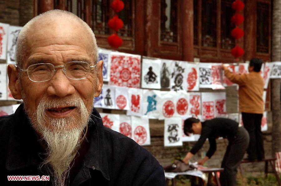 File photo taken on April 12, 2007 shows a papercutting artisan displays his works at a temple fair in Luoyang City, central China's Henan Province. Temple fair in central China area is an important social activity for local people. The ancient temple fairs in central China were ceremonious sacrificial rituals. As time goes by, the focus of temple fair activities has shifted from "gods" to "people". The modern temple fair in central China is a platform of displaying folk culture as well as a channel for commodity circulation. According to statistics from the provincial cultural sector, there are about 35,000 temple fairs each year in Henan. (Xinhua/Wang Song)