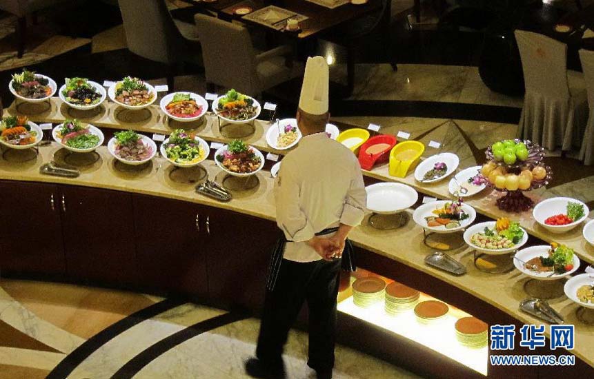 A chef looks at the dishes to buffet restaurant before closing, in a five-star hotel in Chongqing on Jan 19, 2013. (Photo/Xinhua)