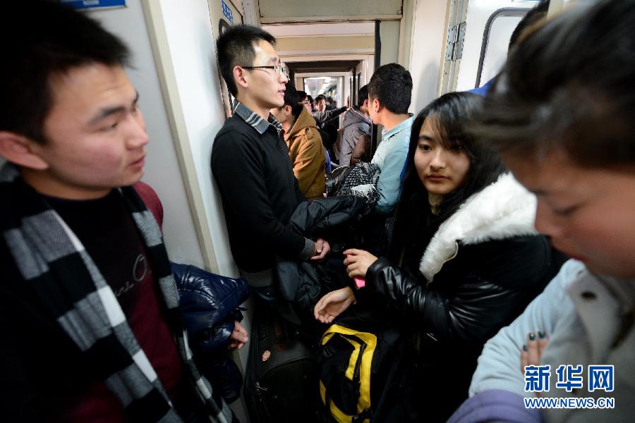 Sui Bin (C) stands in the corridor of a train, Jan. 19, 2013. “I booked the ticket online a week in advance and found only one soft sleeper ticket and one standing tickets left. Without second thought, I booked the standing one, because soft sleeper is too expensive for me.” (Photo/Xinhua)
