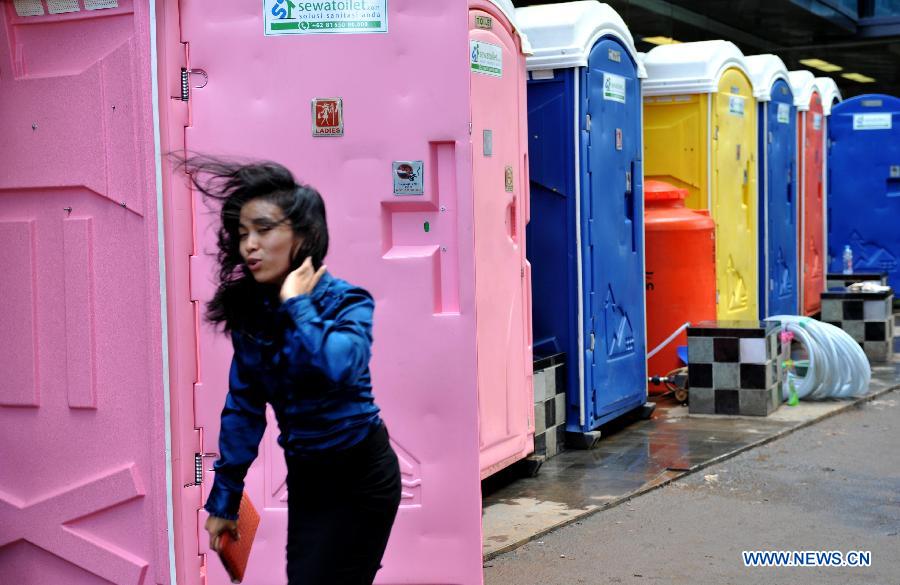 A woman walks past temporary toilets while the sanitation in the office building is failed by flood waters in Jakarta, Indoensia, Jan. 23, 2013. (Xinhua/Agung Kuncahya B.) 