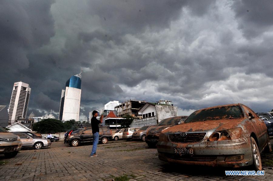 A man takes picture of some cars covered with mud from a flooded basement in Jakarta, Indoensia, Jan. 23, 2013. (Xinhua/Agung Kuncahya B.) 