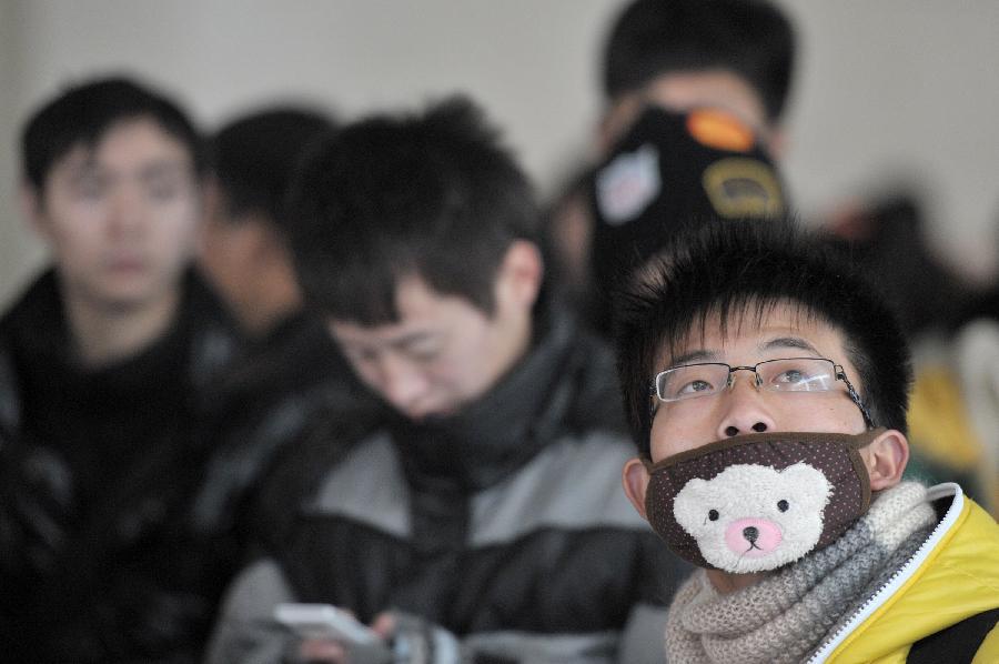 A student with a mask is seen in the waiting hall of the Hefei Train Station in Hefei, capital of east China's Anhui Province, Jan. 23, 2013. Hefei witnessed a student travel peak as winter holidays started in recent days. (Xinhua/Guo Chen)