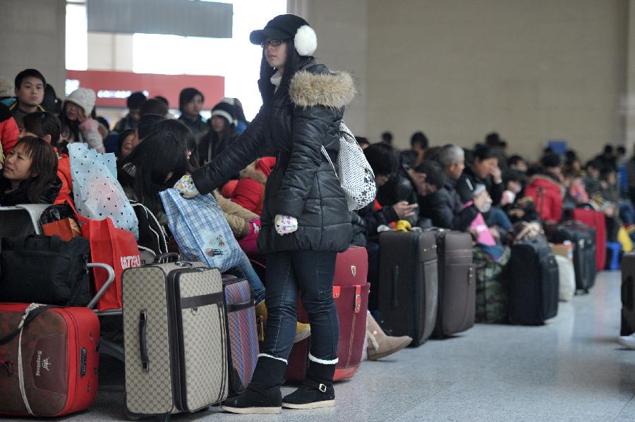 A student stands in queue in the waiting hall of the Hefei Train Station in Hefei, capital of east China's Anhui Province, Jan. 23, 2013. Hefei witnessed a student travel peak as winter holidays started in recent days. (Xinhua/Guo Chen)