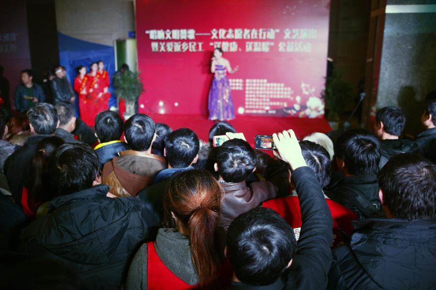 Passengers watch the performance presented by volunteers at the station in Hangzhou, capital of east China's Zhejiang Province, Jan. 23, 2013. A group of volunteers visited the train station in Hangzhou, offering the passengers hot ginger beverage, snacks and Spring Festival Couplets. Stations in Hangzhou embraced more passengers ahead of the Spring Festival travel peak. (Xinhua/Cui Xinyu) 