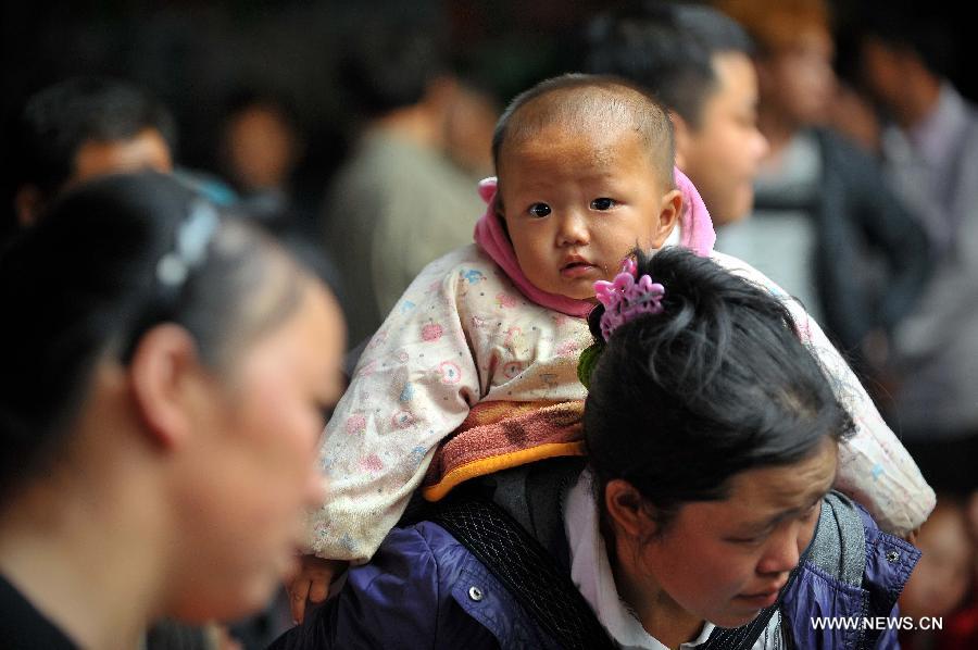 A woman carrying a baby prepares to board a ship at the Xiuying Port in Haikou, capital of south China's Hainan Province, Jan. 24, 2013. Haikou witnessed a travel rush on Thursday as the Spring Festival draws near. (Xinhua/Guo Cheng)