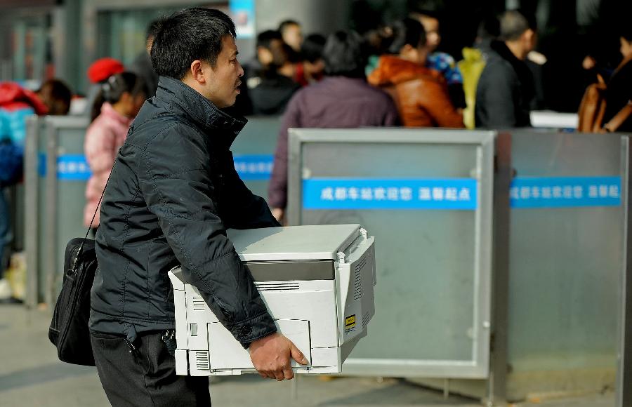 A man carries a printer on the square of the train station in Chengdu, capital of southwest China's Sichuan Province, Jan. 24, 2013. As the spring festival approaches, more than more people started their journey home. (Xinhua/Xue Yubin) 