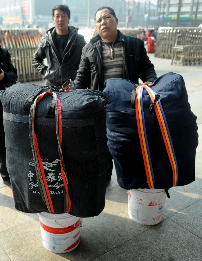 CHENGDU, Jan. 24, 2013 (Xinhua) -- Two men rest behind their luggage on the square of the train station in Chengdu, capital of southwest China's Sichuan Province, Jan. 24, 2013. As the spring festival approaches, more than more people started their journey home. (Xinhua/Xue Yubin)