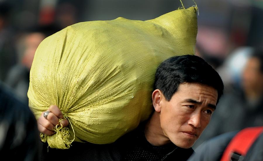 A man shouldering a bag walks on the square of the train station in Chengdu, capital of southwest China's Sichuan Province, Jan. 24, 2013. As the spring festival approaches, more than more people started their journey home. (Xinhua/Xue Yubin) 