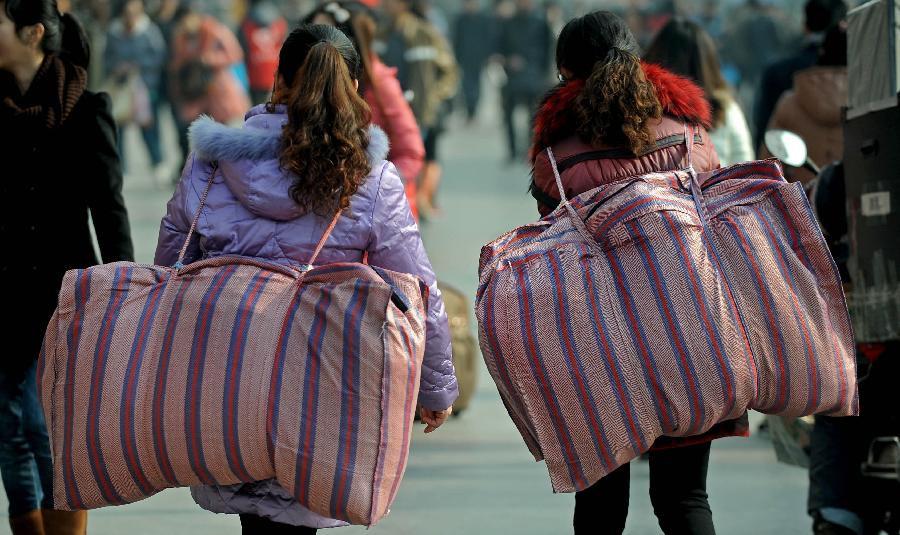 Passengers carry their luggage on the square of the train station in Chengdu, capital of southwest China's Sichuan Province, Jan. 24, 2013. As the spring festival approaches, more than more people started their journey home. (Xinhua/Xue Yubin)