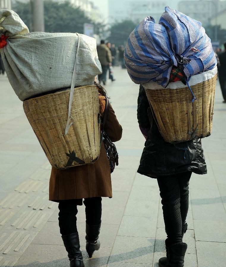 Passengers carry their luggage on the square of the train station in Chengdu, capital of southwest China's Sichuan Province, Jan. 24, 2013. As the spring festival approaches, more than more people started their journey home. (Xinhua/Xue Yubin) 