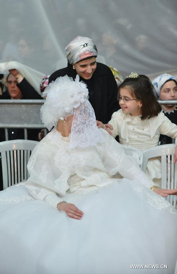 The bride, the first granddaughter of Grand Rabbi of the Satmar hassidic dynasty Rabbi Zalman Leib Teitelbaum, talks with her relatives during her wedding in Israeli town of Beit Shemesh, on Jan. 24, 2013. The wedding was held here from the evening of Jan. 23 to the morning of Jan. 24. Some 5,000 guests attended the traditional Jewish wedding. (Xinhua/Yin Dongxun)