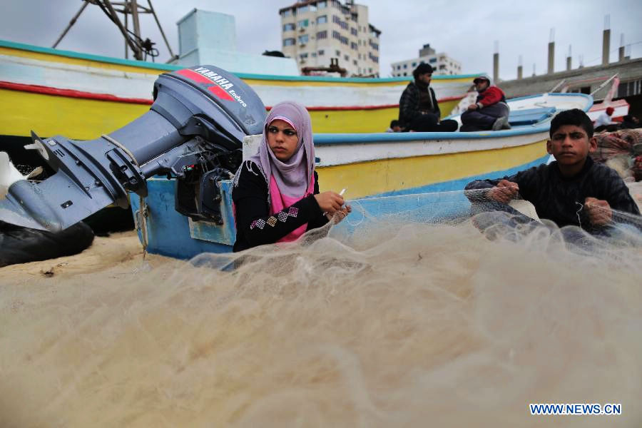 Palestinian fisherwoman Madeline Kolab repairs her fishing net on the sea beach in Gaza City, on Jan. 23, 2013. Sixteen-year-old Madeline Kolab is a fisherwoman. Her father, a veteran fisherman, became disabled, and therefore, she quit school after the ninth grade to take the job. "I don't care about what people say. I only care about feeding my family although fishing in Gaza is risky. The Israeli navy allows boats only a few miles offshore." Kolab said. (Xinhua/Wissam Nassar)