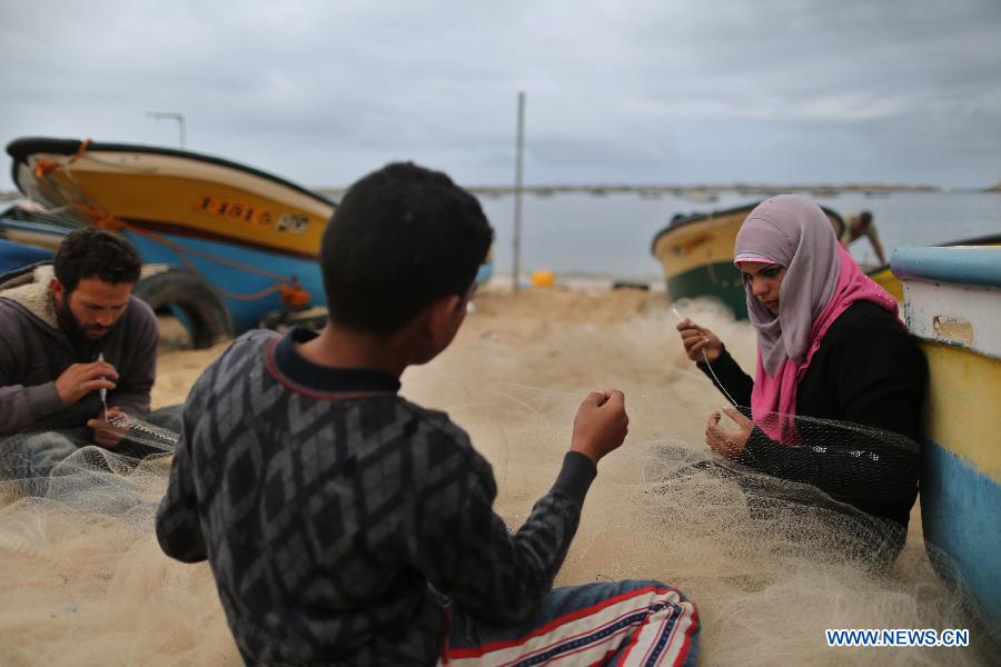 Palestinian fisherwoman Madeline Kolab repairs her fishing net on the sea beach in Gaza City, on Jan. 23, 2013. Sixteen-year-old Madeline Kolab is a fisherwoman. Her father, a veteran fisherman, became disabled, and therefore, she quit school after the ninth grade to take the job. "I don't care about what people say. I only care about feeding my family although fishing in Gaza is risky. The Israeli navy allows boats only a few miles offshore." Kolab said. (Xinhua/Wissam Nassar)