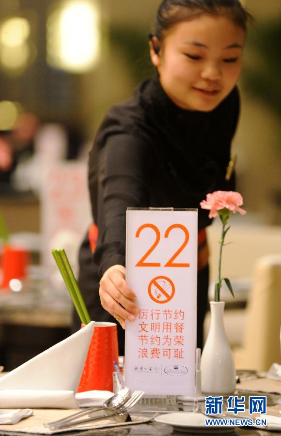 A restaurant waitress places a sign with food-saving slogan on the table in Qingdao, Shandong province, Jan. 24.  Stirred by an exposure on astonishing food waste on Chinese tables, “Did you empty the dishes today?” has become the most popular question in China. As response, restaurants and government departments take actions to eliminate food waste. Showing an empty dish also turns a new fashion among Chinese netizens. (Xinhua/Li Ziheng)