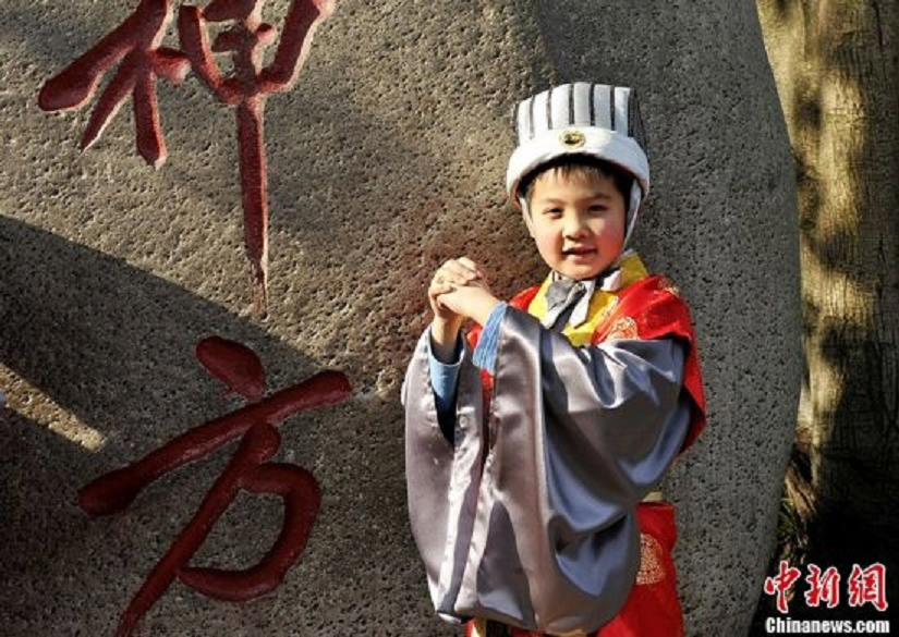 A child in costumes of "God of Happiness" meets the media in the Wuhou Memorial Temple in Chengdu, Sichuan Province, January 24, 2013. They will perform at a temple fair during the Spring Festival. (Photo: CNS/An Yuan)