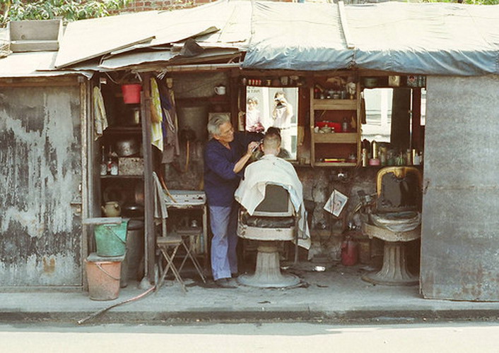 An old man shaves his client’s hair in a "hair salon". (Photo/Chinadaily.com.cn)