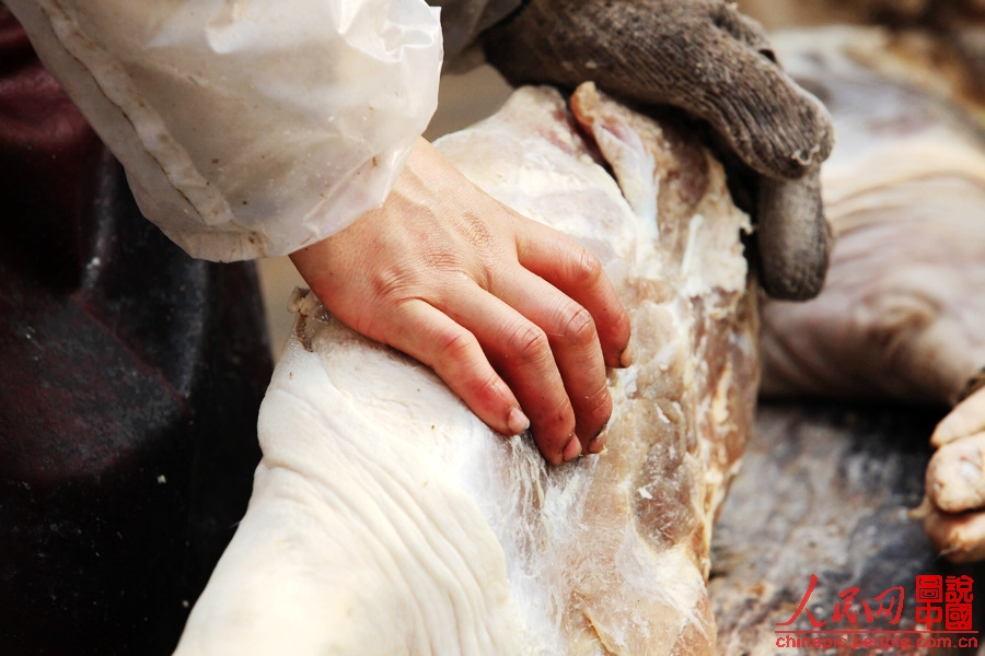 The worker shapes the ham by massaging it.