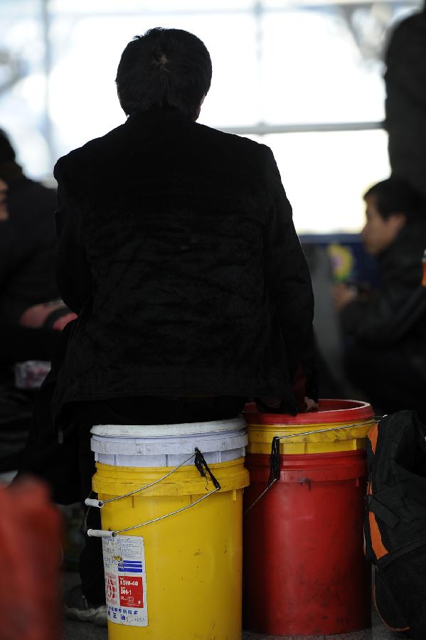 A passenger sits on plastic buckets, which can be used as both containers and seats during the trip, while waiting to board a train at the Yinchuan Railway Station in Yinchuan, capital of northwest China's Ningxia Hui Autonomous Region, Jan. 25, 2013. The most important Chinese holiday, the Spring Festival, falls on Feb. 10 and migrants want to get home to see their families. The Ministry of Railways forecast the holiday travel rush, which starts on Jan. 26, will last until March 6. (Xinhua/Wang Peng)