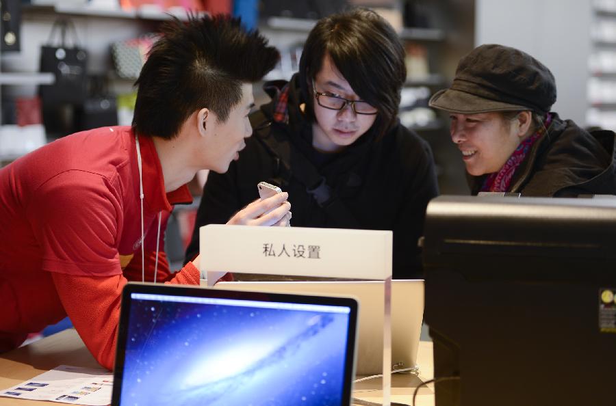 A working staff introduces apple products to customers at Wangfujin Apple Store in Beijing, capital of China, Jan. 25, 2013. Apple Store held a sales activity on Friday, during which customers could enjoy special pricing online and at Apple retail stores on apple products. (Xinhua/Qi Heng) 