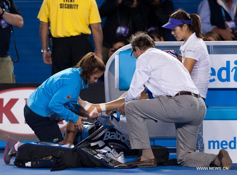 Li Na (R) of China receives treatment from medical staff after falling during the women's singles final match against Victoria Azarenka of Belarus at the 2013 Australian Open tennis tournament in Melbourne, Australia, Jan. 26, 2013. Azarenka won 2-1 to claim the title. (Xinhua/Bai Xue) 