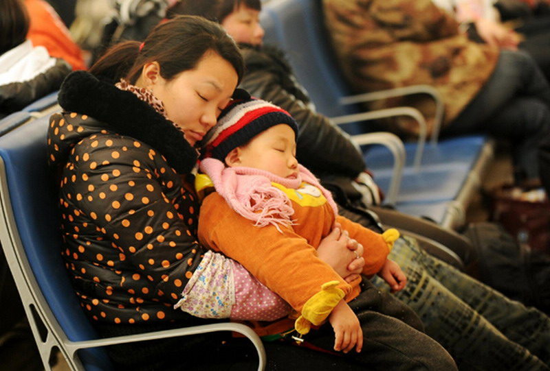 A kid falls asleep with his mother at Shijiazhuang Bus Station, Hebei province, Jan 26, 2013. (Photo/Xinhua)