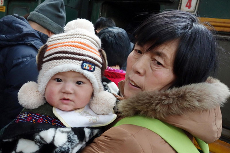 A woman with a baby waits for board a train at Tianjin Railway Station, Jan 26, 2013. (Photo/Xinhua)
