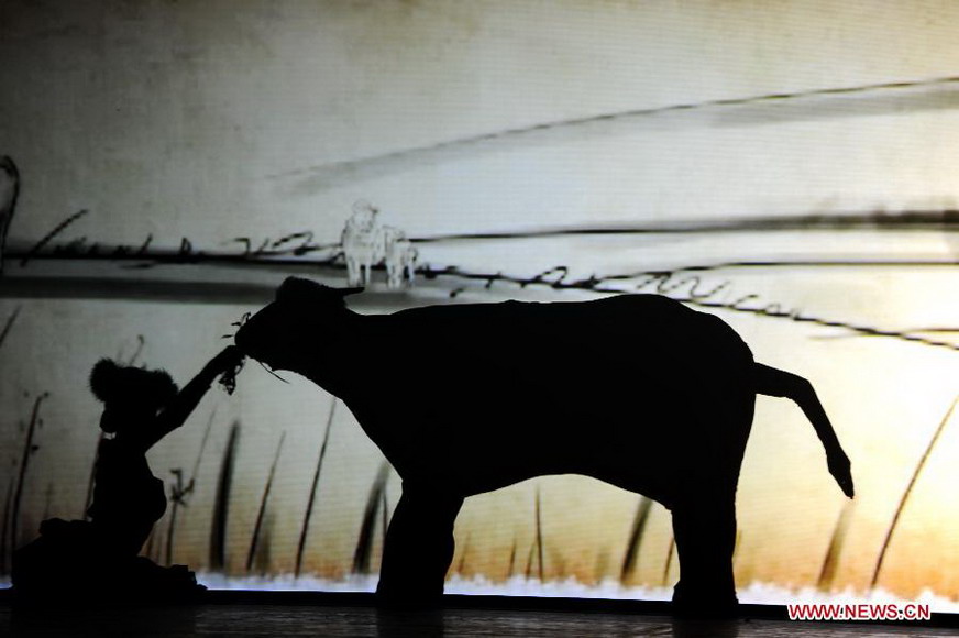 The image of an actress feeding a cow combined from five artists is silhouetted during a live show at a scenic resort in Changbaishan of northeast China's Jilin Province, Jan. 26, 2013. A live show reflecting the folk culture derived from the Changbai Mountains area was staged here on Saturday. The show presented the audience with dances, acrobatics, magic performances. (Xinhua/Zhang Nan) 