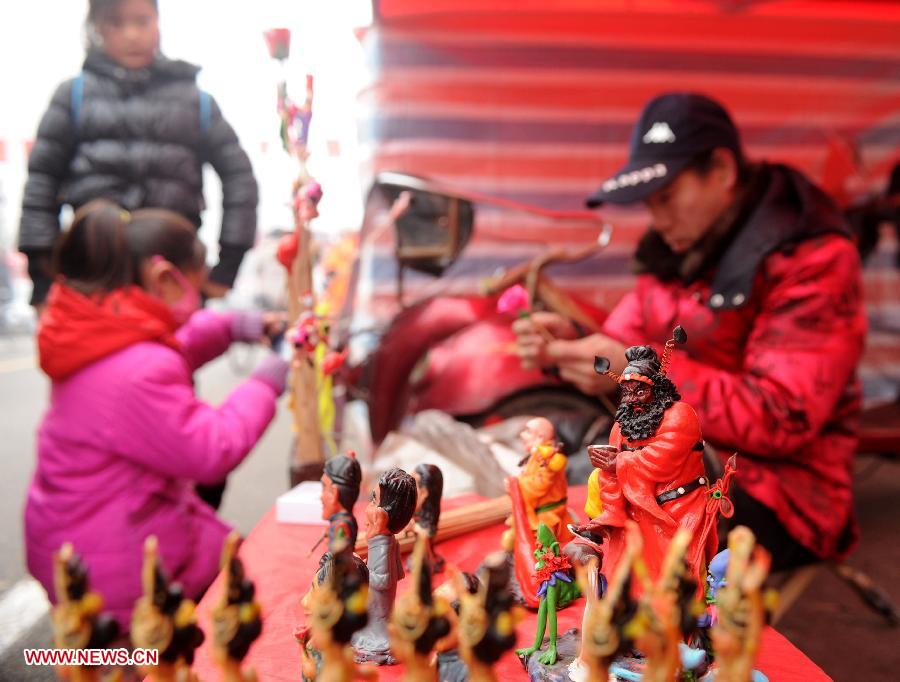 People watch a man making clay figurine at a market in Shijiazhuang, capital of north China's Hebei Province, Jan. 27, 2013. The market offers local customers goods and supplies for the coming Spring Festival which falls on Feb. 10 this year.(Xinhua/Zhu Xudong)