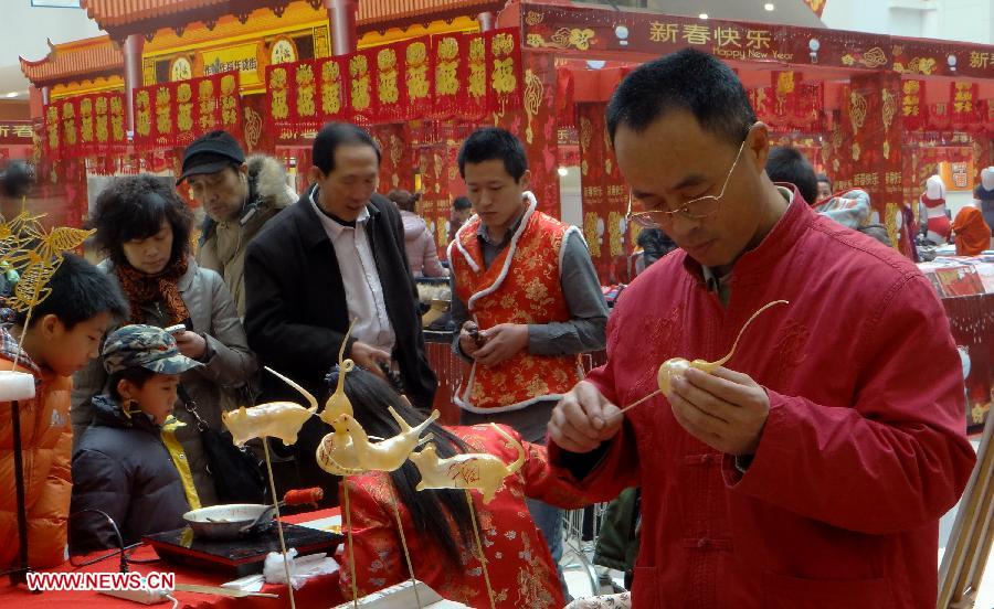 A craftsman (front) makes sugar statuette for customers as people do shopping for the upcoming Spring Festival in Beijing, capital of China, Jan. 27, 2013. Retailers all around the country take many kinds of sales boosting measures to attract shoppers as Chinese Spring Festival approaches. (Xinhua/Li Xin)