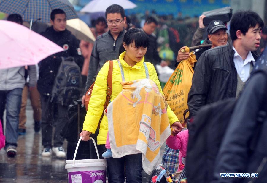 Passengers make their way to the railway station in the rain on the square of the Nanning Railway Station in Nanning, capital of south China's Guangxi Zhuang Autonomous Region, Jan. 26, 2013. As the Spring Festival, which falls on Feb. 10 this year, draws near, lots of people rushed to start their journey home. (Xinhua/Huang Xiaobang)